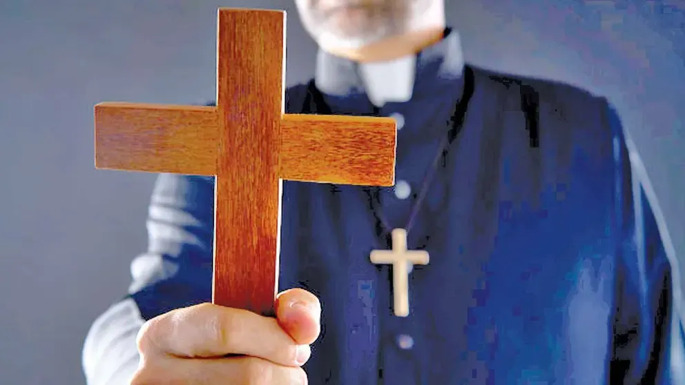 Un sacerdote de la Iglesia Católica sostiene una cruz. 