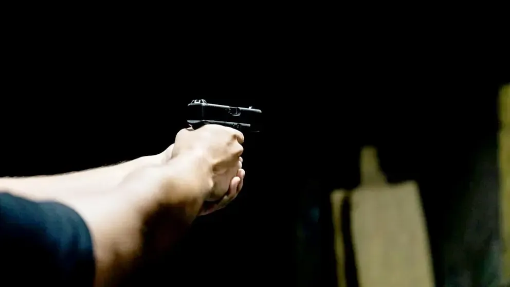 Fotografía ilustrativa de un hombre sosteniendo un arma de fuego.